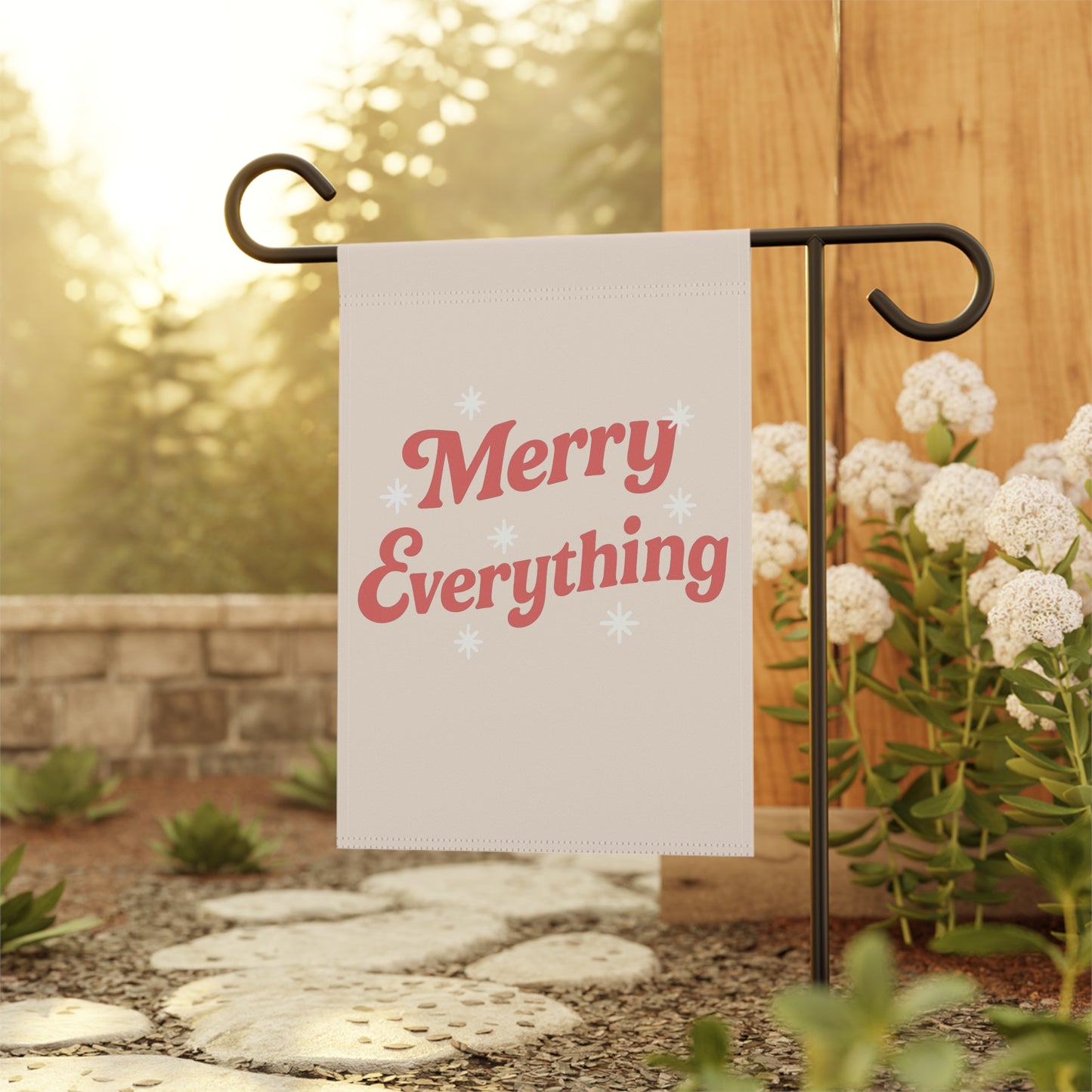 Garden flag with 'Merry Everything' text on a stand outdoors.