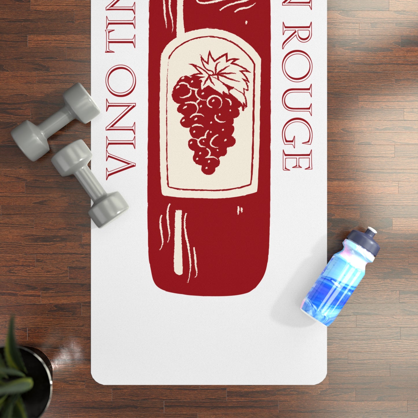 Yoga mat with wine bottle design on a wooden floor with dumbbells and a water bottle.