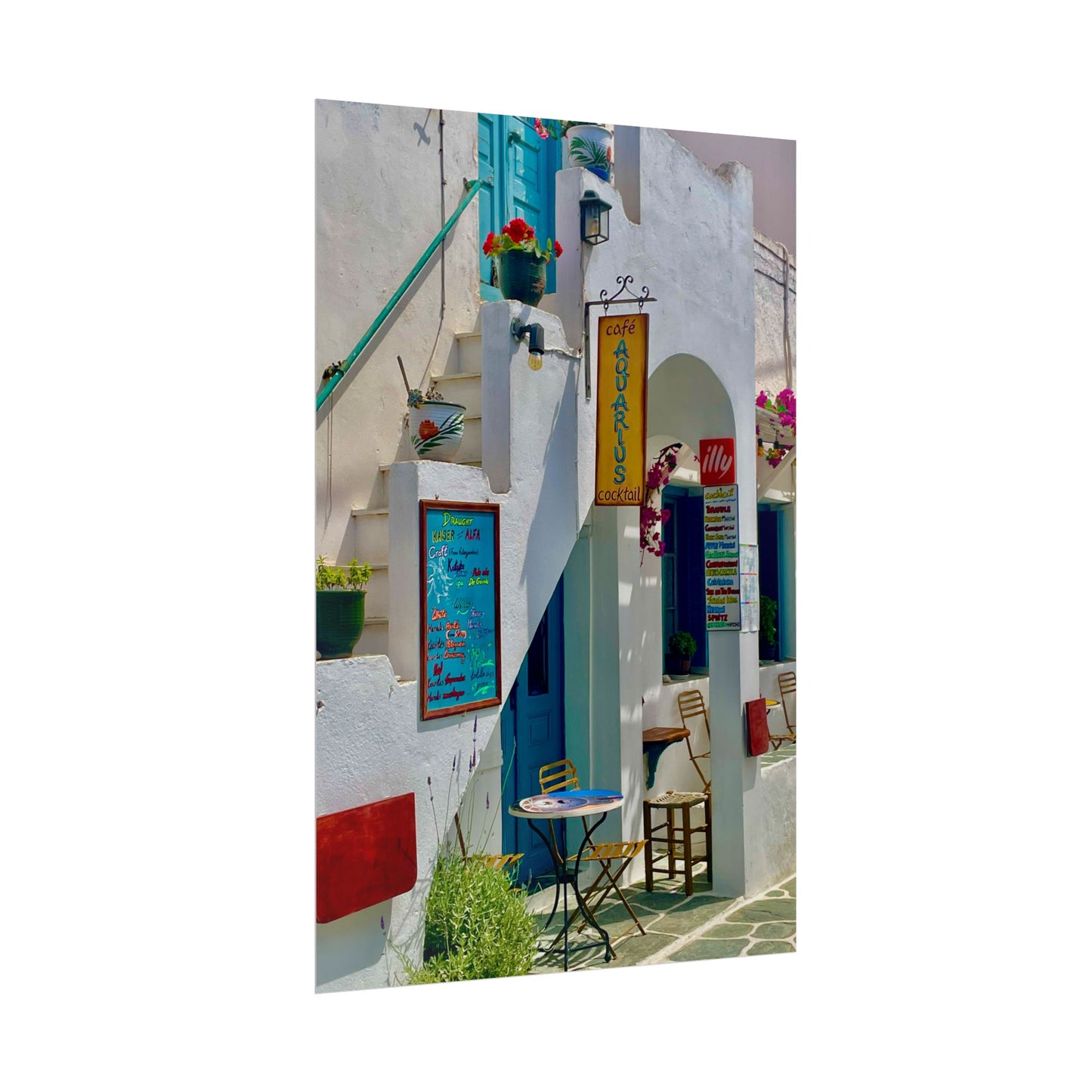 Colorful street scene with white buildings, blue doors, and a small table with chairs.