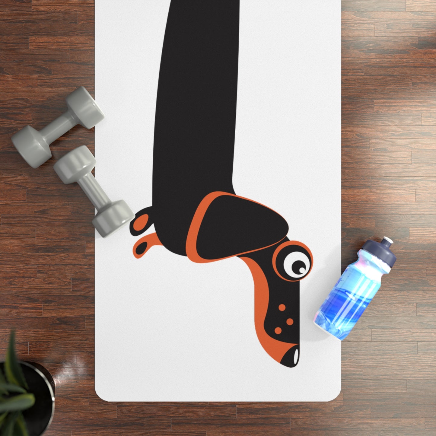 Yoga mat with cartoon dachshund dog, dumbbells, and water bottle on a wooden floor