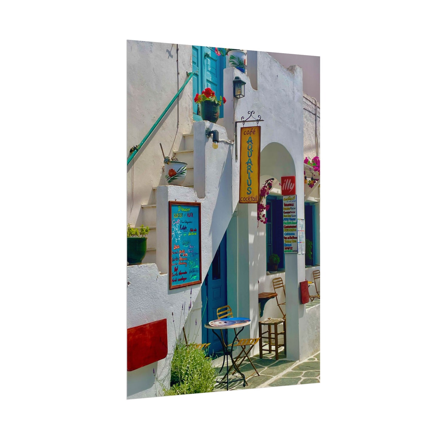 Colorful street scene with white buildings, blue doors, and a small table with chairs.