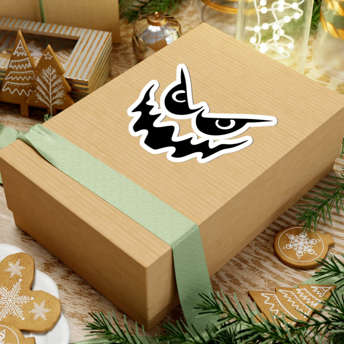 Wooden gift box with a green ribbon and decorative sticker on a festive background with cookies and lights.