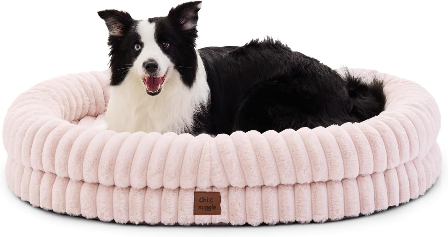 Dog lying on a pink plush dog bed with a visible brand label.