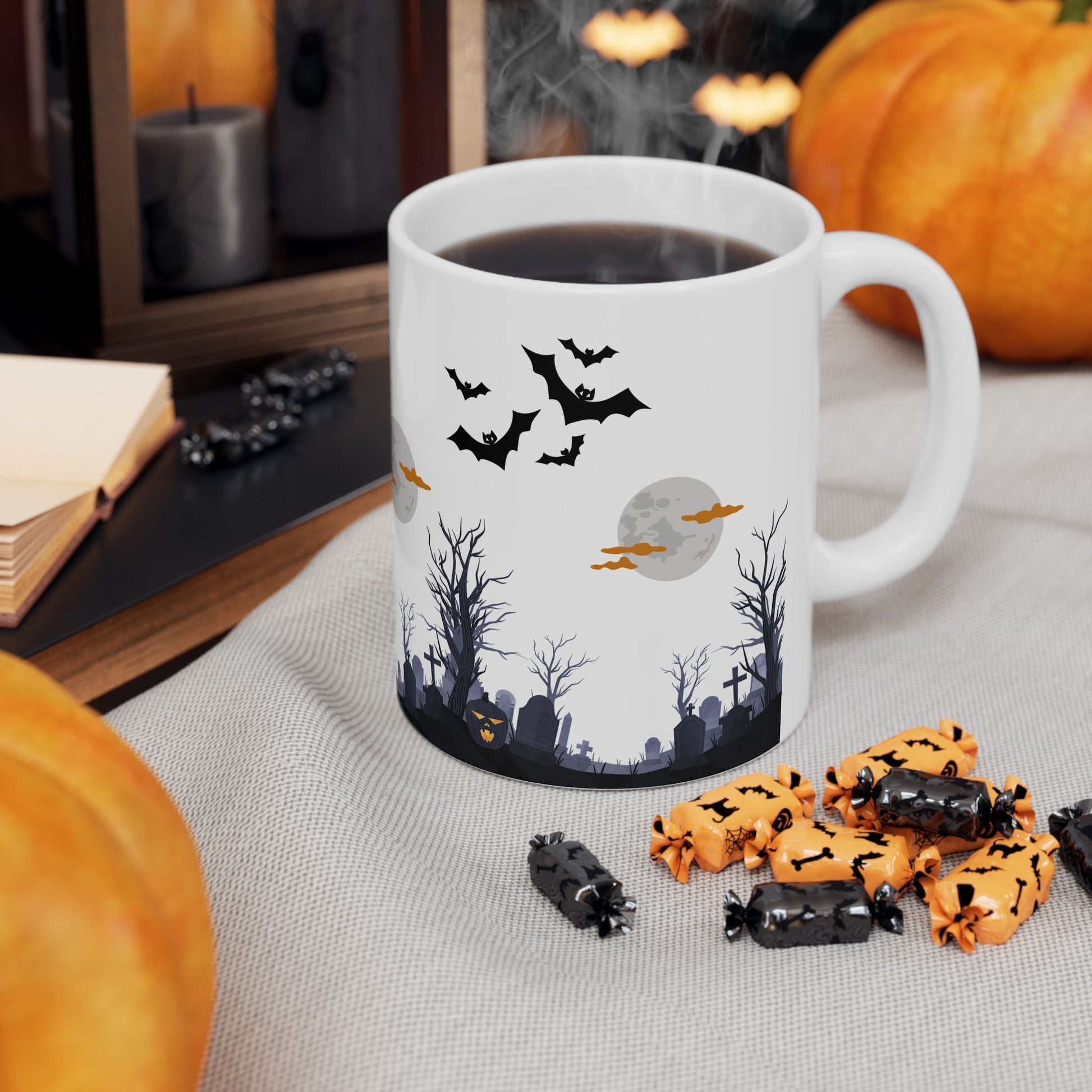 Halloween-themed mug with bats and pumpkins on a table with candy.