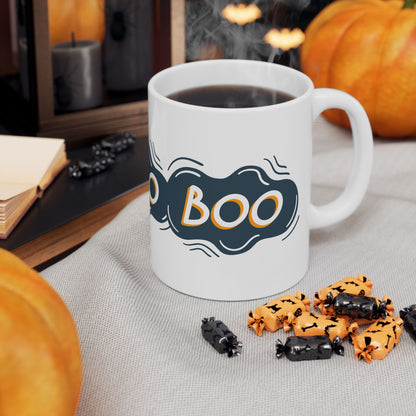 White mug with 'BOO' design, steaming hot chocolate, Halloween-themed cookies, and pumpkins on a table.