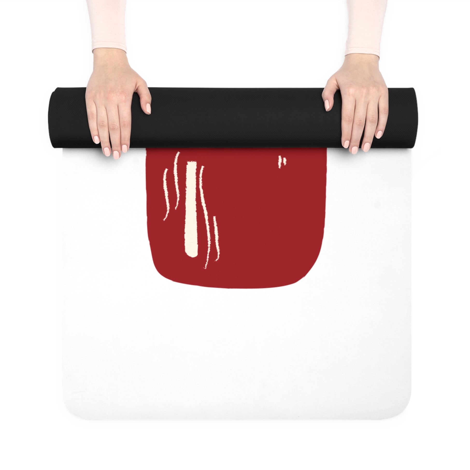 Person holding a rolled-up black yoga mat with a red and white design on a white background
