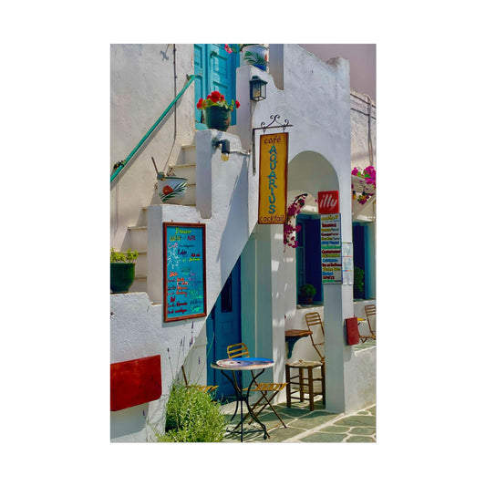 Colorful outdoor setting with white walls, blue doors, and a small table with chairs.