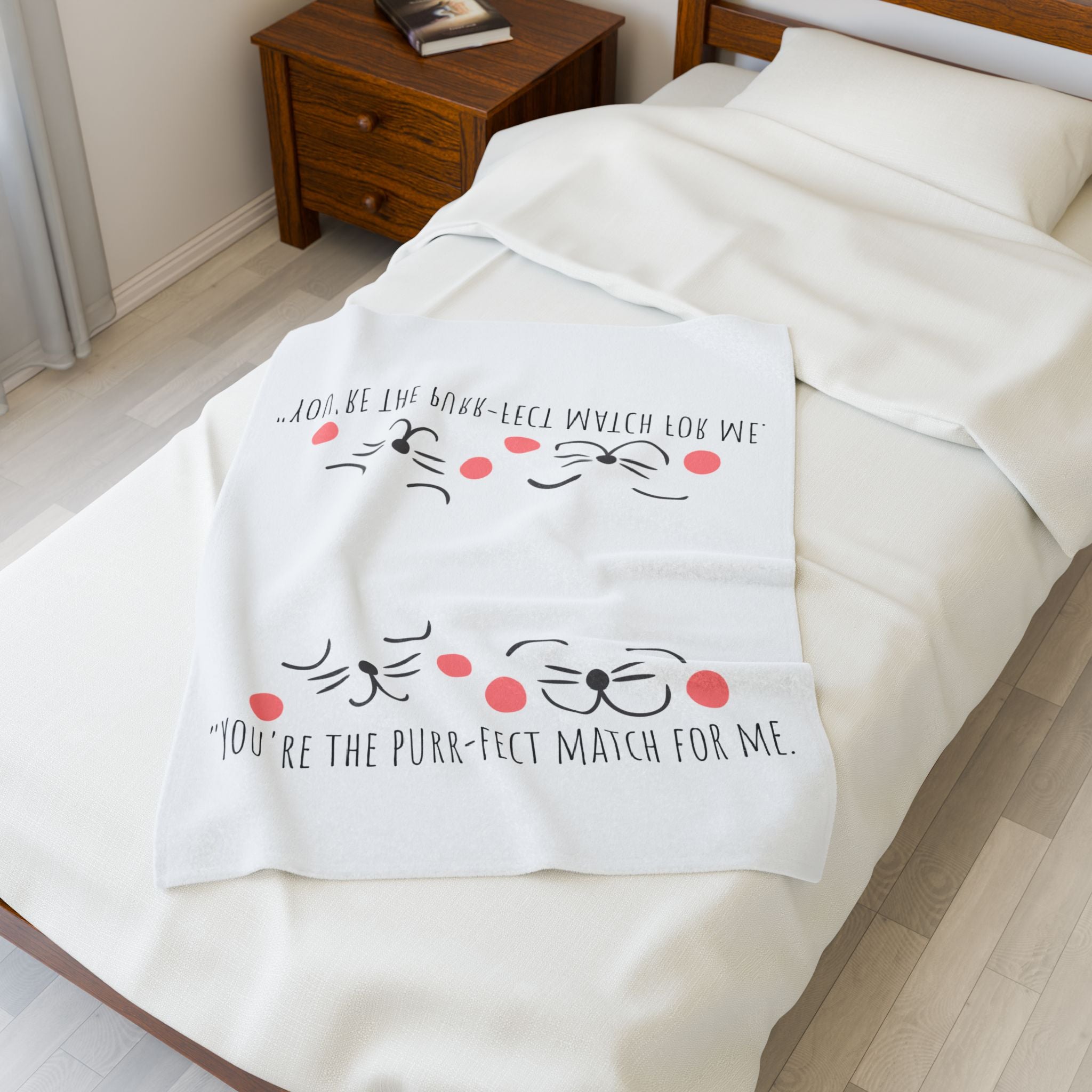 White 'Purr-fect Match' cat plush blanket folded on a bed