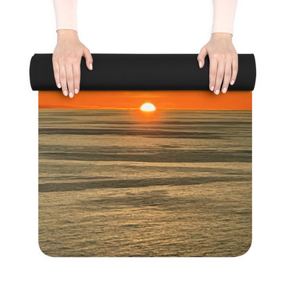 Yoga mat with sunset design held by hands on a white background