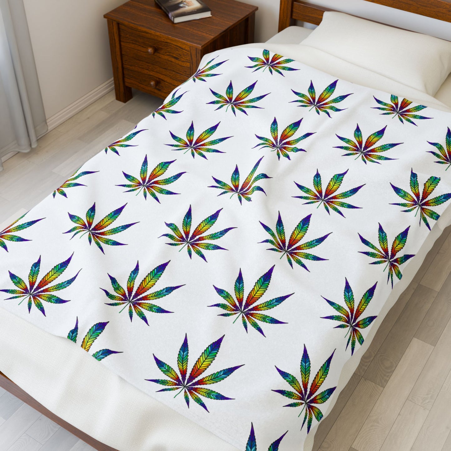 Cannabis Leaf Blanket with rainbow patterns laying on bed 