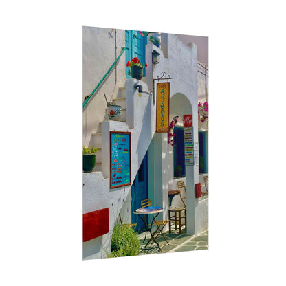 Colorful street scene with white buildings, blue doors, and a small table with chairs.