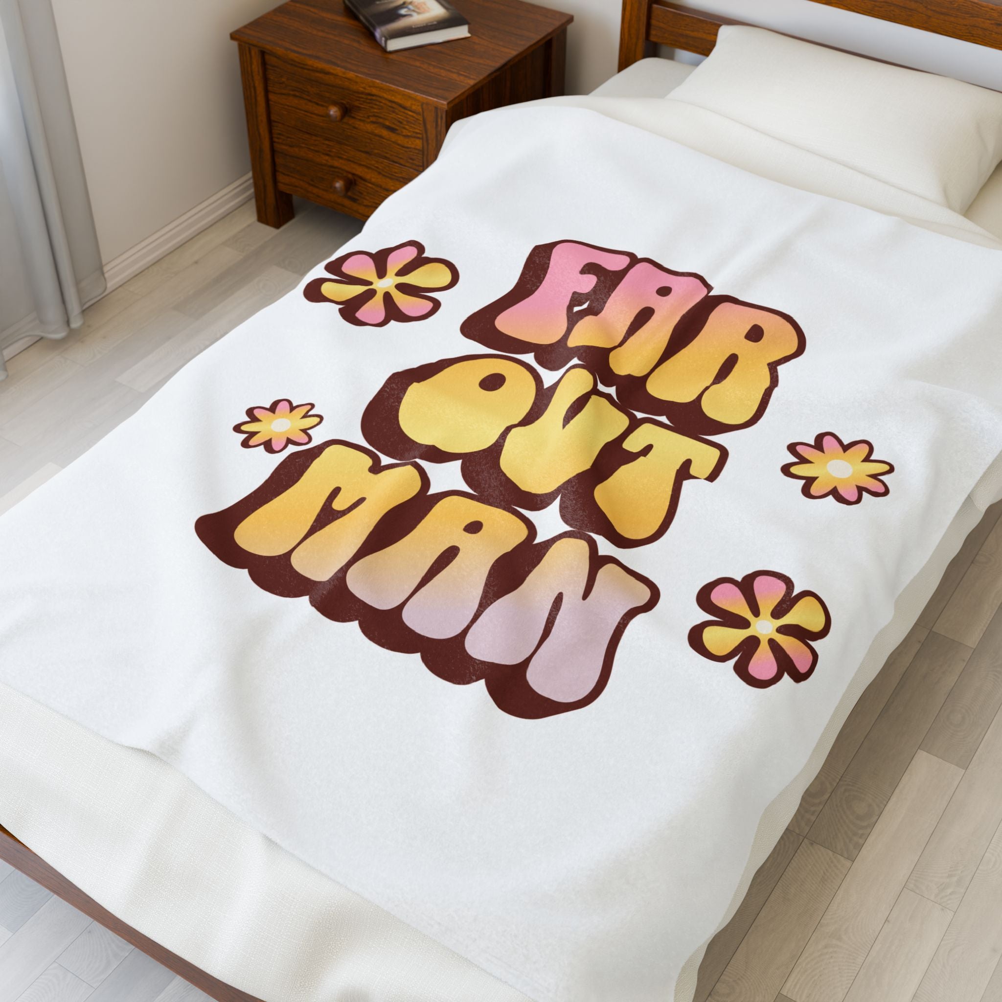 Blanket with 'Far Out Man' text and flowers on a bed in a bedroom.