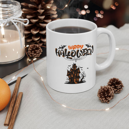 White mug with 'Happy Halloween' design featuring a haunted house, surrounded by decorative items on a table.