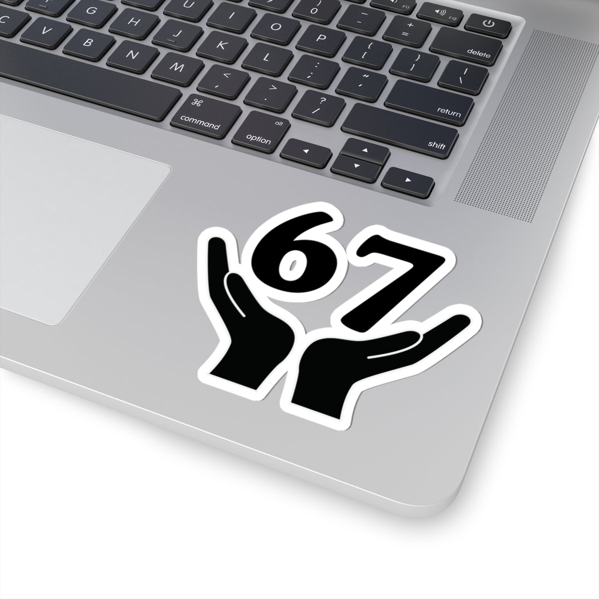 Laptop with a sticker of two hands holding the number 67 on a white background