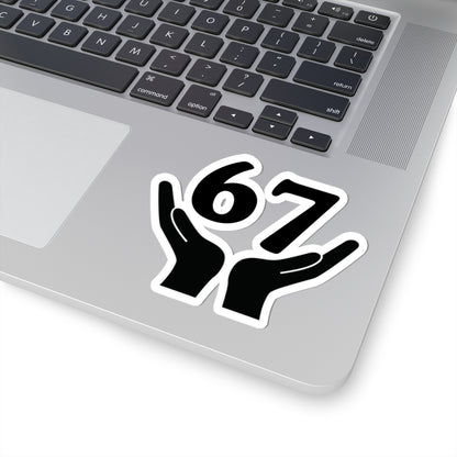 Laptop with a sticker of two hands holding the number 67 on a white background