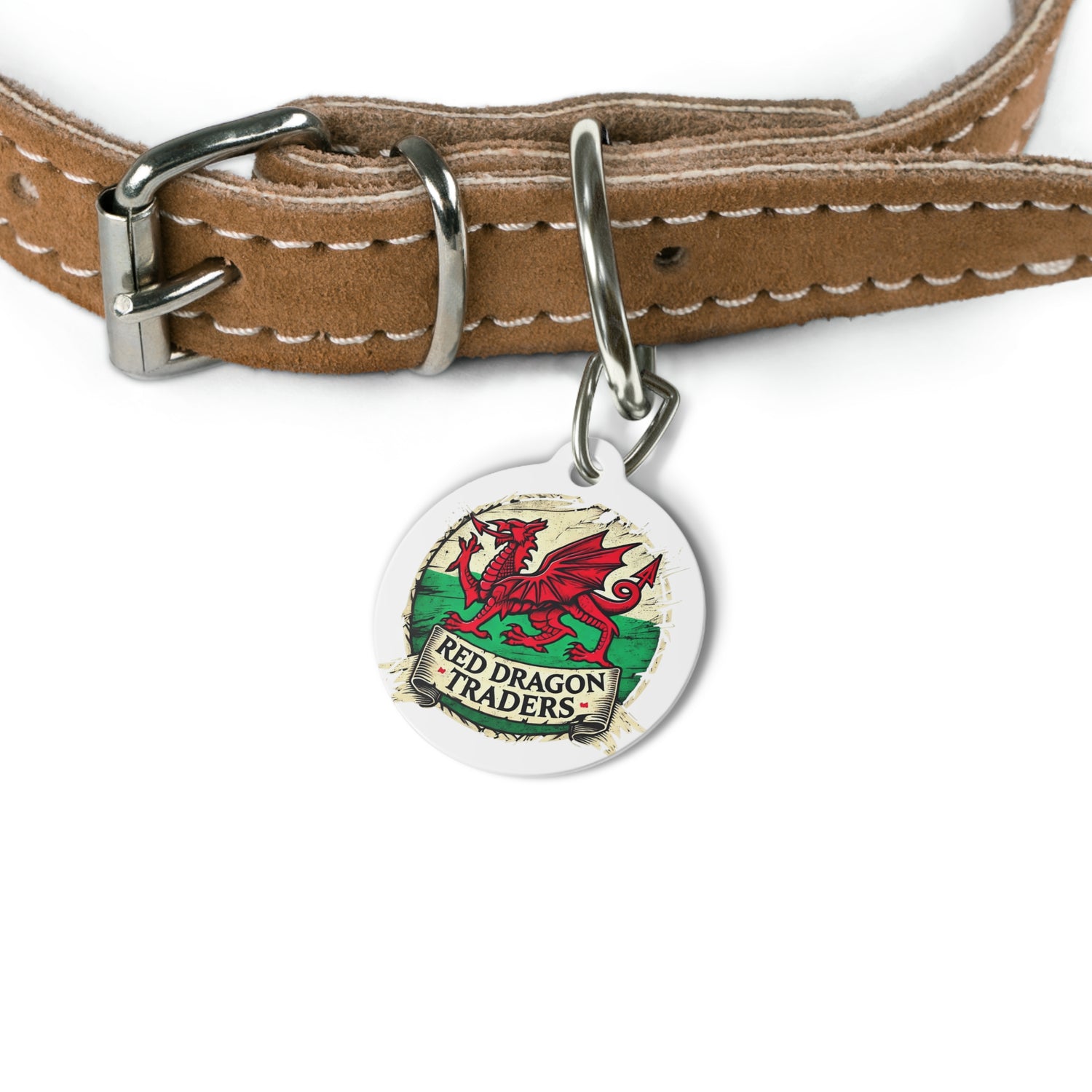 A round white metal pet tag with a red dragon illustration and the text 'RED DRAGON TRADERS', attached to a brown leather collar with a metal clip.