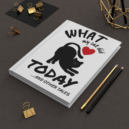 Cat Journal titled 'What my cat did today...and other tales' on a dark surface with office supplies.