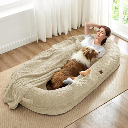 Woman lying on a large pet bed with a dog, in a bright room with curtains.